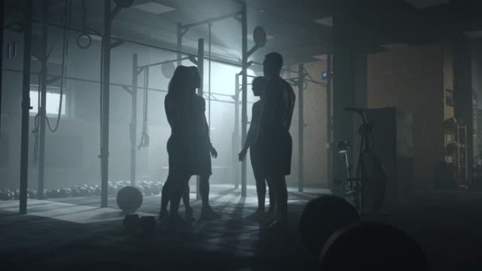 四个运动员在体育馆里聊天，黑暗中的男人和女人的黑暗剪影