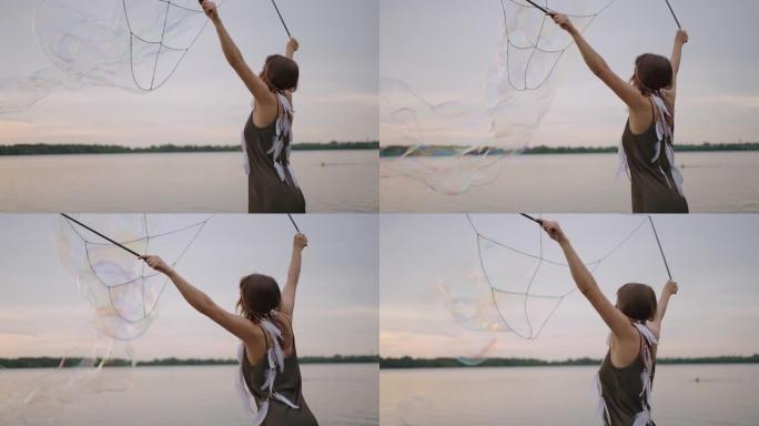 一位年轻的女孩艺术家使用巨大的肥皂泡展示魔术。在日落时使用棍棒和绳索创建肥皂泡，以展示戏剧马戏团表演