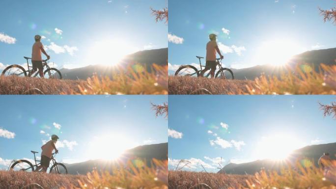 成熟的男性电子自行车手登上山坡，观看日落