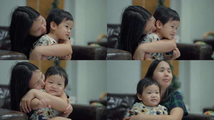 快乐的母亲在沙发上拥抱可爱的孩子儿子