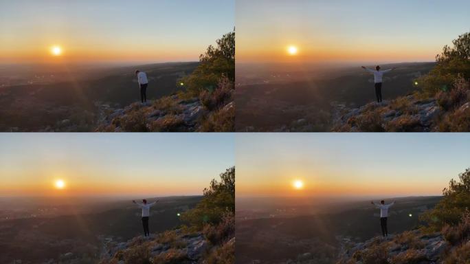 男人站在山顶上，看着日落