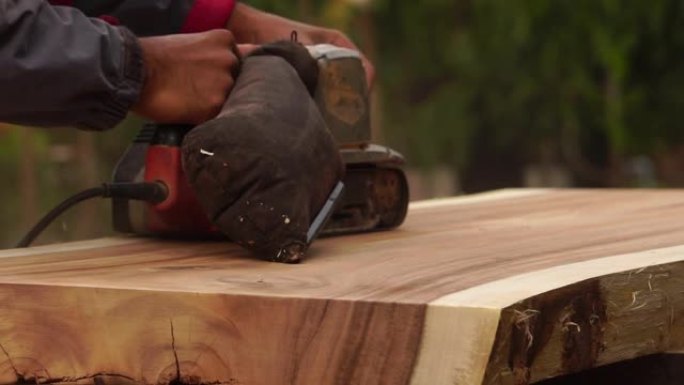 男木匠正在使用电动木工工具在户外工作