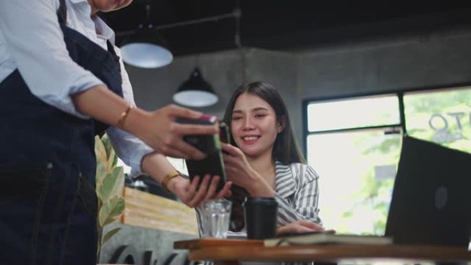 年轻女子在咖啡馆用手机付款