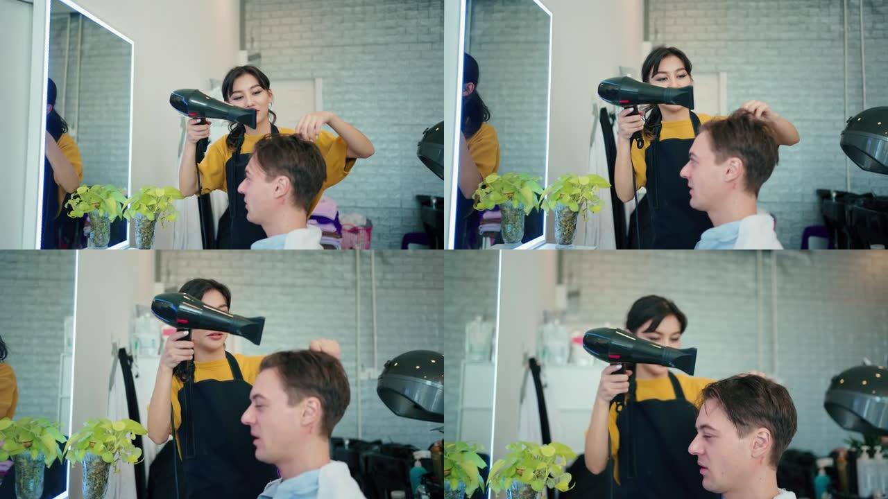 年轻的女理发师在吹干顾客头发时使用吹风机和圆刷