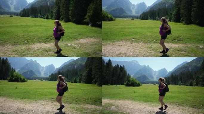 孕妇在山上徒步旅行，微笑着看着郁郁葱葱的绿色草地和落基山脉的景色
