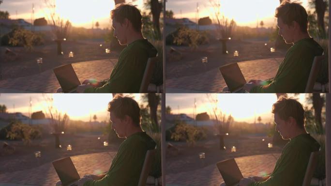 年轻人在户外日落时使用笔记本电脑