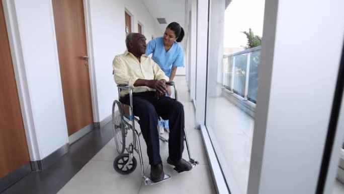 拉丁美洲护士在医院与一名坐在轮椅上的老人交谈，非常关心和愉快