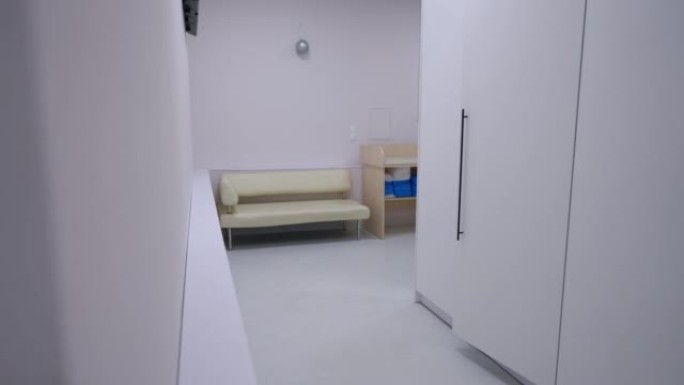 现代医疗诊所室内等候区。实时摄像机从左向右移动，进入室内舒适的沙发进入医院走廊。