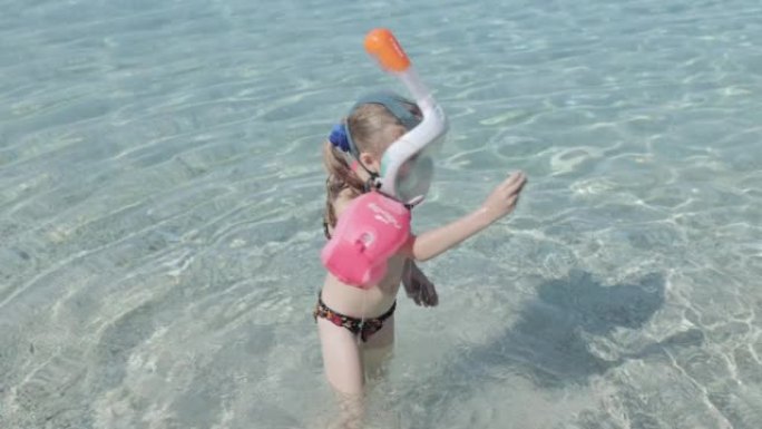 孩子在清澈的海水中带着浮潜面罩游泳。