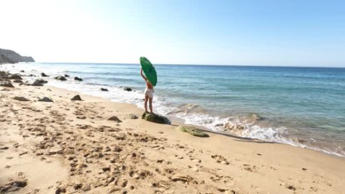 日出时分，年轻女子背着冲浪板沿着空旷的海滩前行