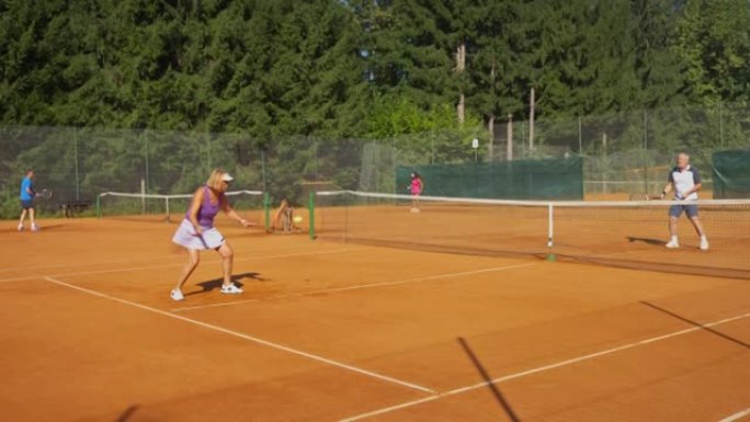 CS高级女子和男子在阳光下在室外球场打网球