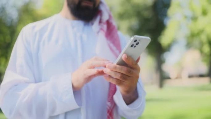使用智能手机拍摄的大胡子穆斯林男子穿着传统的阿拉伯白色连衣裙
