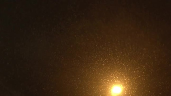 黑暗中的冬季背景。雨刷在车窗上移动。大雪和路灯