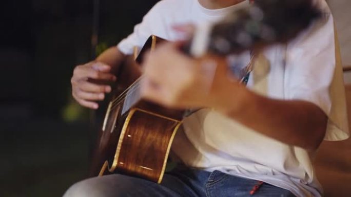 年轻的亚洲夫妇作为音乐家在户外露营时一起弹吉他。
