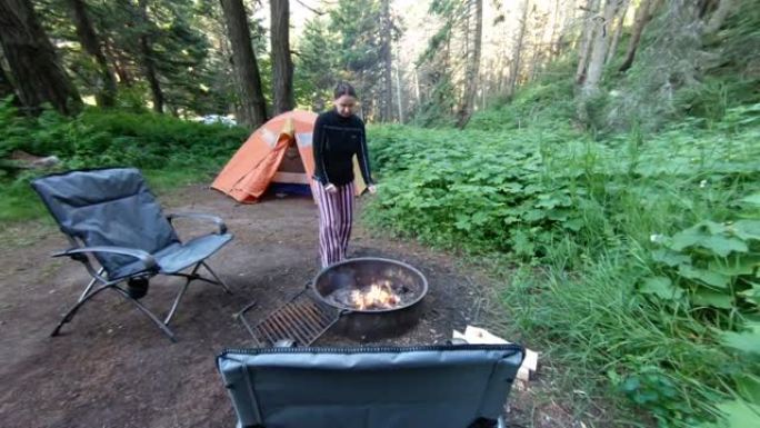 女人站在树林里的室外火坑旁
