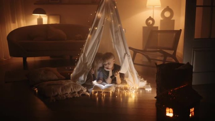 童年快乐的时刻，小男孩和女孩晚上在房子的房间里玩玩具帐篷