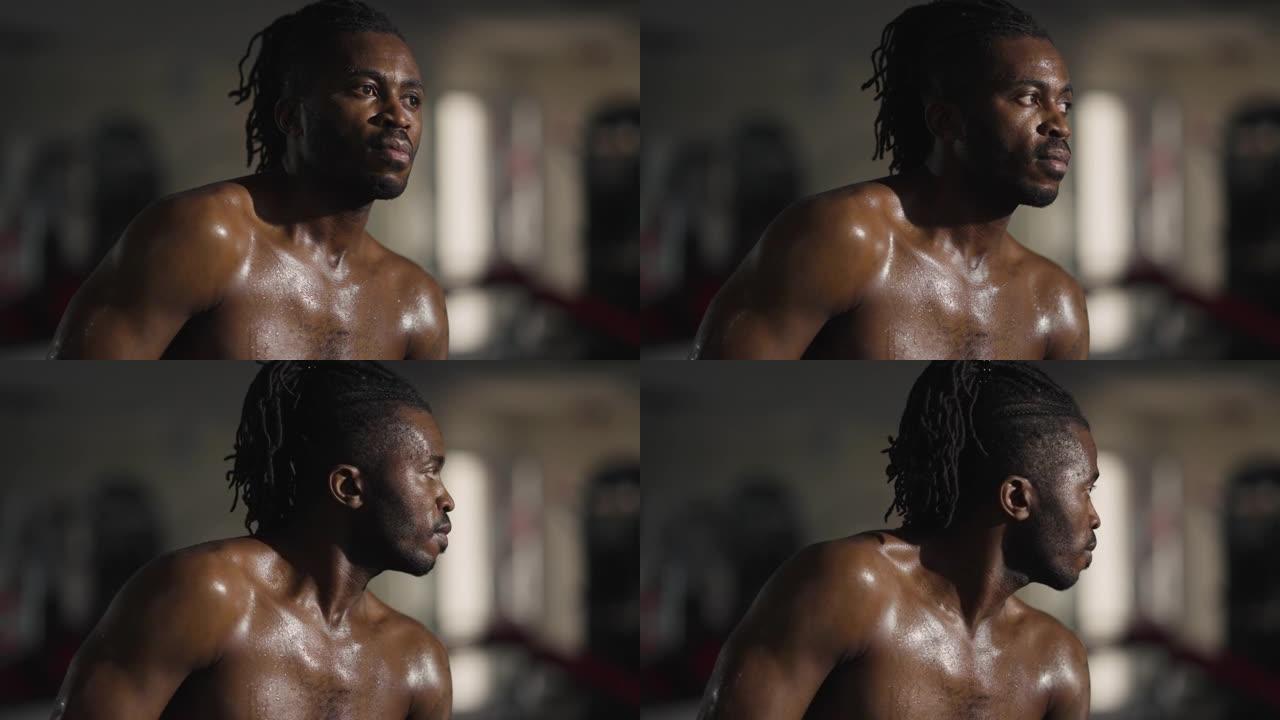 出汗的非洲裔美国自信男子坐在健身房呼吸的肖像。持久强壮英俊的运动员在室内休息。阳刚之气和健康的生活方