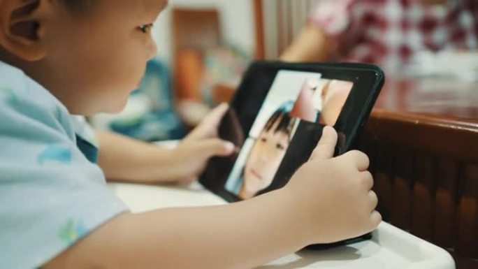 蹒跚学步的孩子在家在数字平板电脑上进行视频通话。