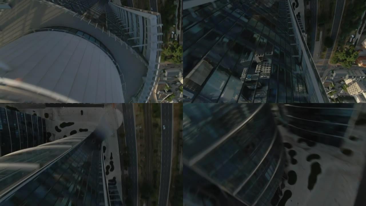 映照蓝天的玻璃摩天大楼。FPV无人机快速转弯向下移动建筑物