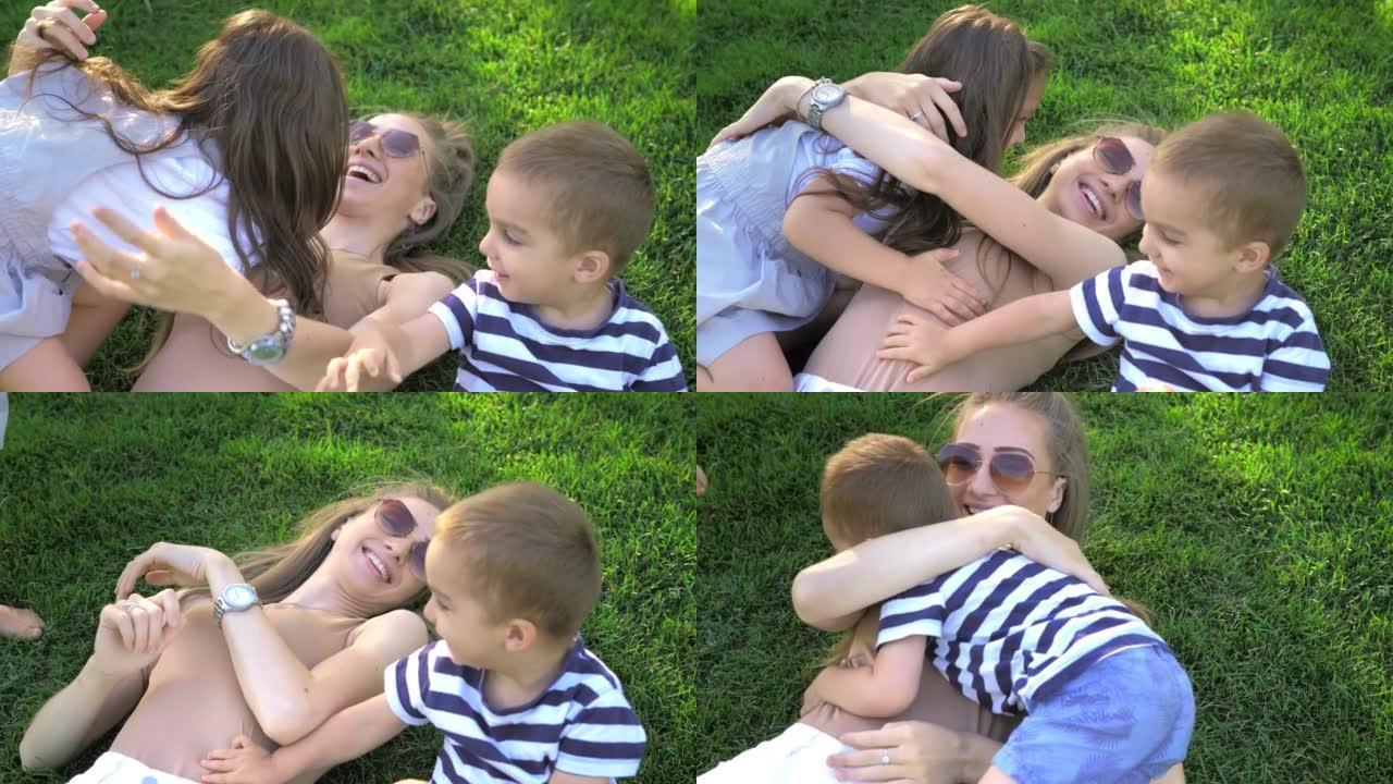 妈妈和她的孩子们躺在公园的草地上，微笑着，拥抱着，看着天空。父母带着儿子和女儿在新鲜空气中玩得开心。