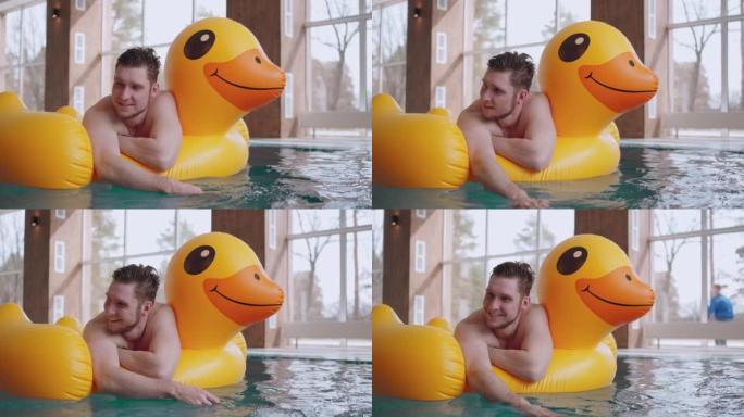 水上乐园的快乐男人，躺在游泳池的充气鸭子上，快乐而放松的男性访客