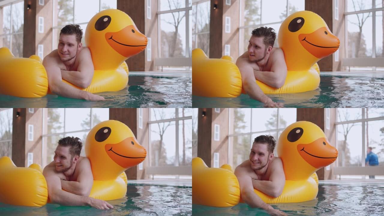 水上乐园的快乐男人，躺在游泳池的充气鸭子上，快乐而放松的男性访客