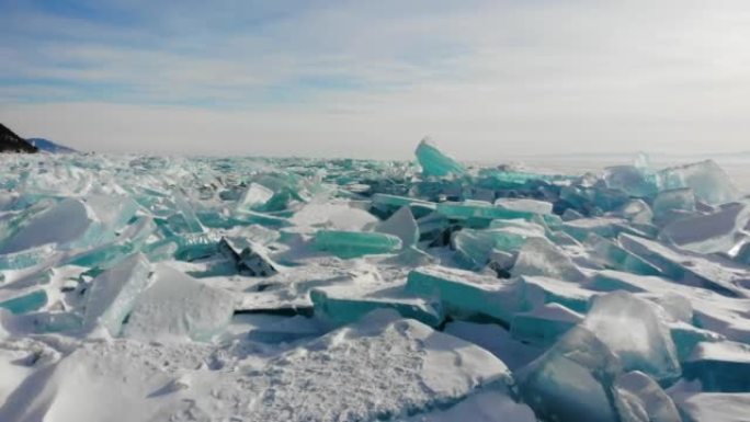 冰冻的贝加尔湖岸边的大块透明冰块。被雪覆盖的驼峰。