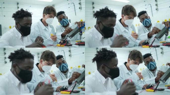 年轻男子在实验室里研究电子设备——戴着口罩