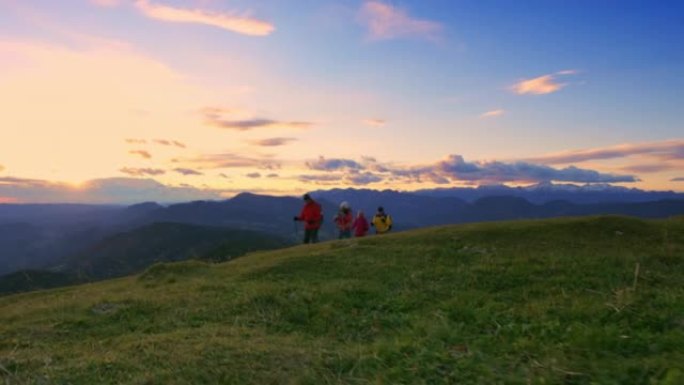 SLO MO四名徒步旅行者在日落时走在山顶上