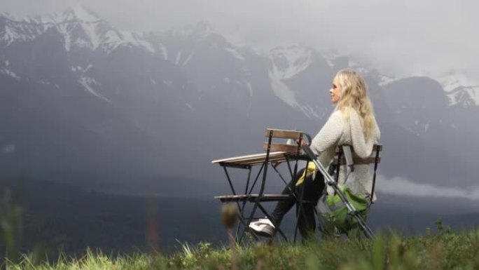 女人在便携式桌子上放松，俯瞰森林，山脉