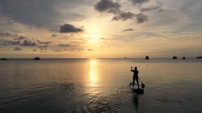 日落时间海上女子桨板的鸟瞰图