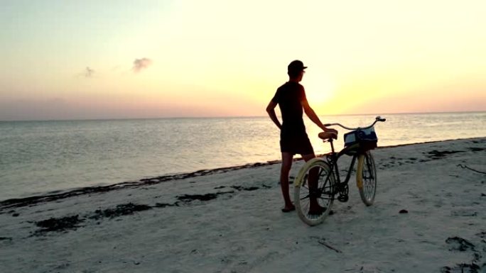 年轻人在沙滩上骑自行车走路