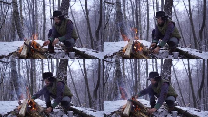 男人在寒冷的冬日在森林里燃烧篝火