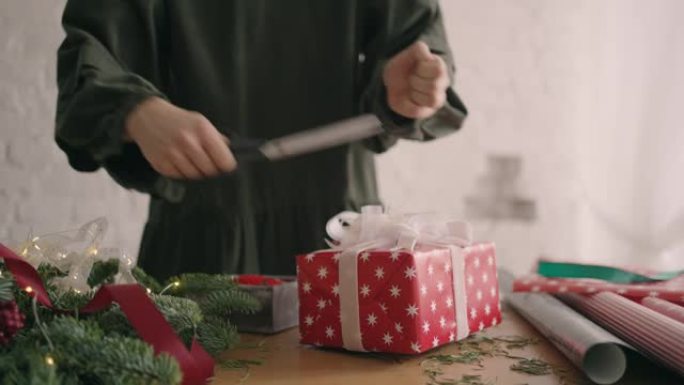 特写: 用绳子装饰包装的盒子。女性在木桌上包装纸板礼品盒，为圣诞节庆祝准备各种装饰物品。