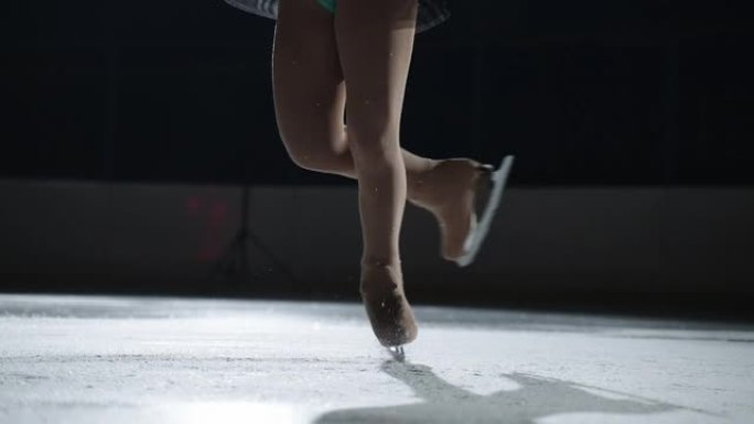女子单人花样滑冰表演，在黑暗的溜冰场上旋转元素时女运动员的腿特写，比赛和示范表演