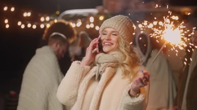 新年之夜，幸福的金发女人在城市广场用手机祝贺，肖像