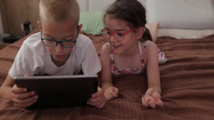 一个兄弟姐妹正在数字平板电脑上玩电子游戏