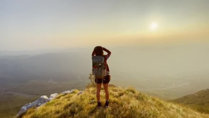 SLO MO TS女徒步旅行者走到山脊的边缘并举起双手