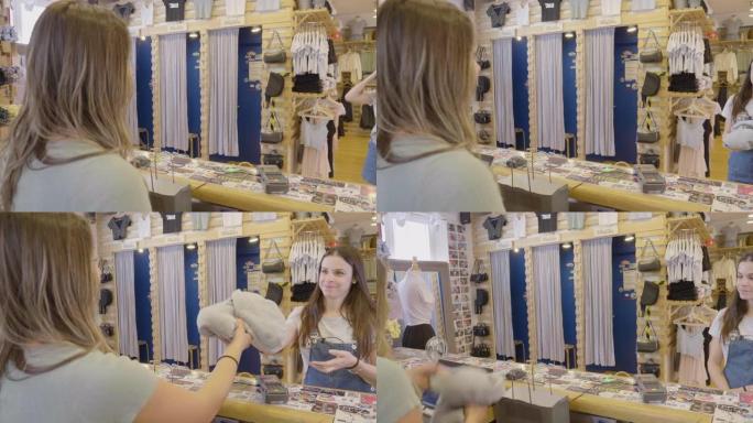 年轻女子在服装店检查女顾客，递给顾客一个袋子