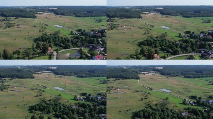 鸟瞰乡村乡村景观。郊区有住宅建筑波兰。农场变成波兰的绿地。鸟瞰农舍，丘陵田地树木森林农业场。