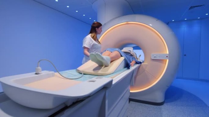DS女性放射学技术人员准备一名女性患者并将其滑入MRI扫描仪