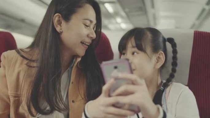 母亲和女儿在飞机上使用智能手机