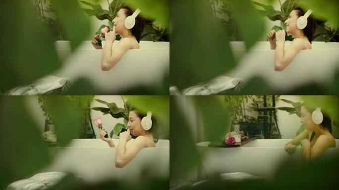 美丽的女人在现代浴室放松。听音乐，拿着玫瑰