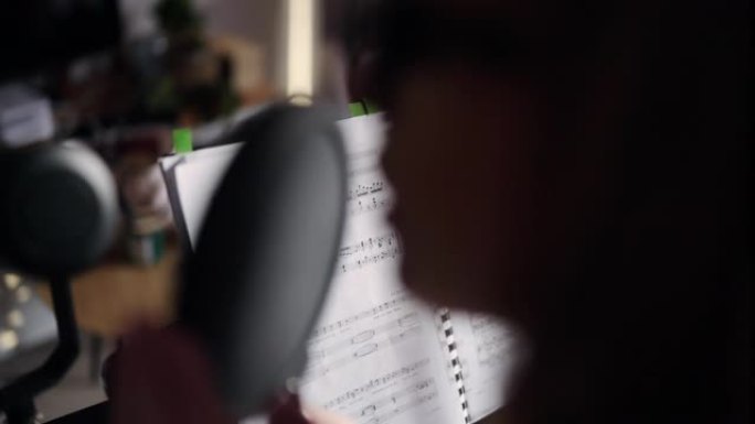 特写的年轻女子弹钢琴，对着麦克风唱圣诞颂歌。音乐录音和歌唱课在家