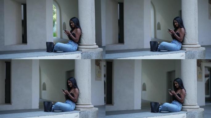 用手机坐在柱子附近的年轻女子