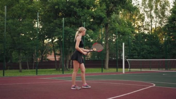年轻的女网球运动员正在弹跳球，并在网球场，训练和友谊赛中服役