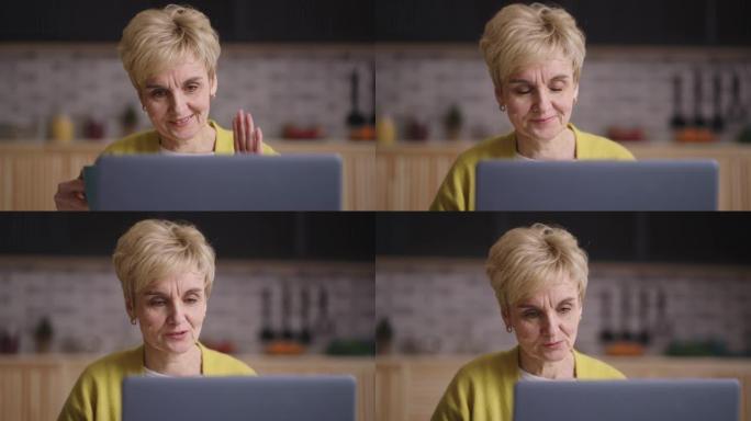 退休妇女正在笔记本电脑上通过视频聊天聊天，坐在家里的厨房里，脸上满是皱纹的微笑女士的肖像