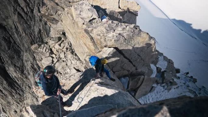 一队登山者沿着陡峭的墙壁移动。高海拔山脉