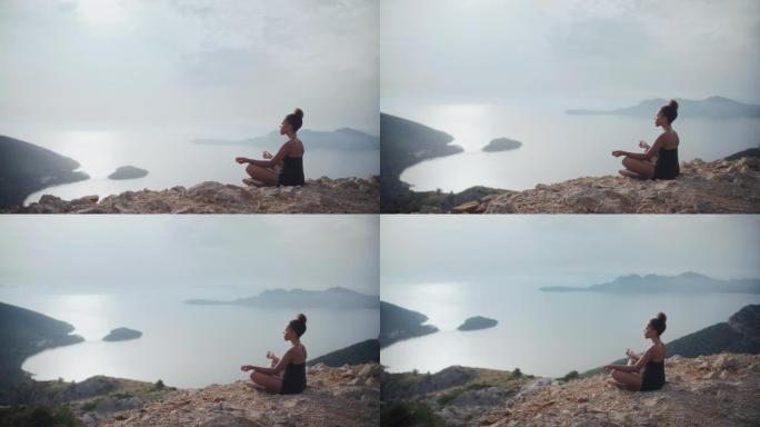 非洲族裔妇女在悬崖顶上冥想，看着莲花位置的阳光明媚的大海