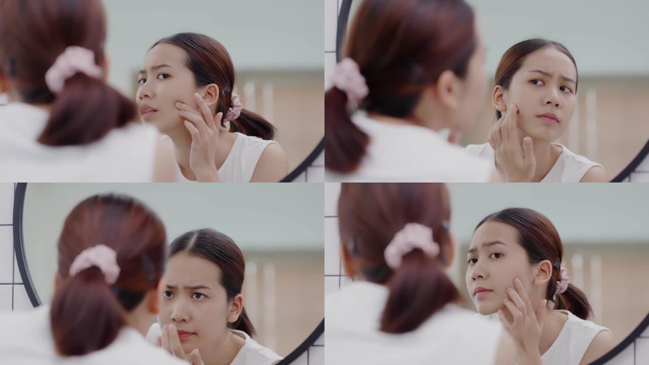 亚洲女孩照镜子担心面部皮肤问题。